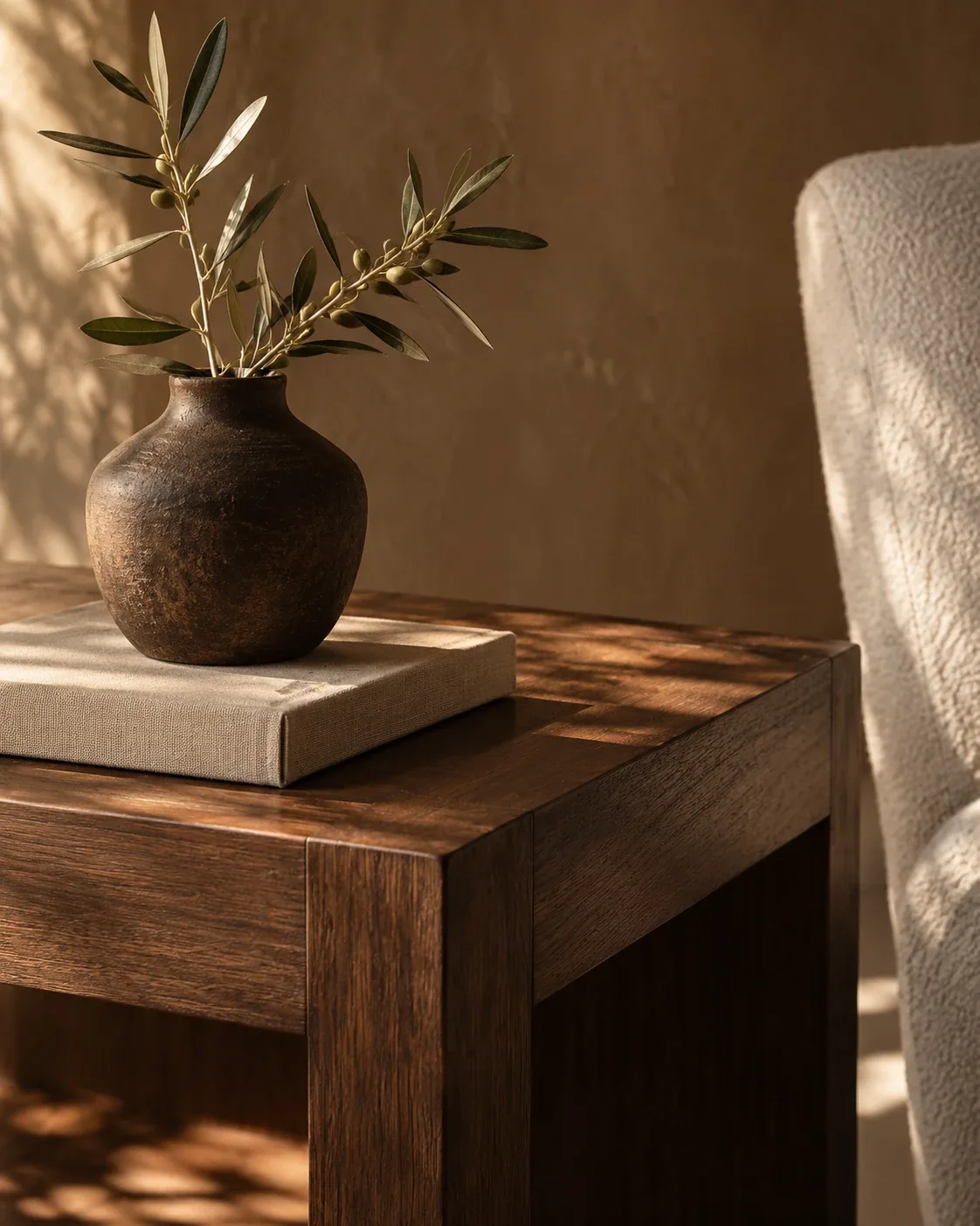 Olive branches in a ceramic vase on a walnut table